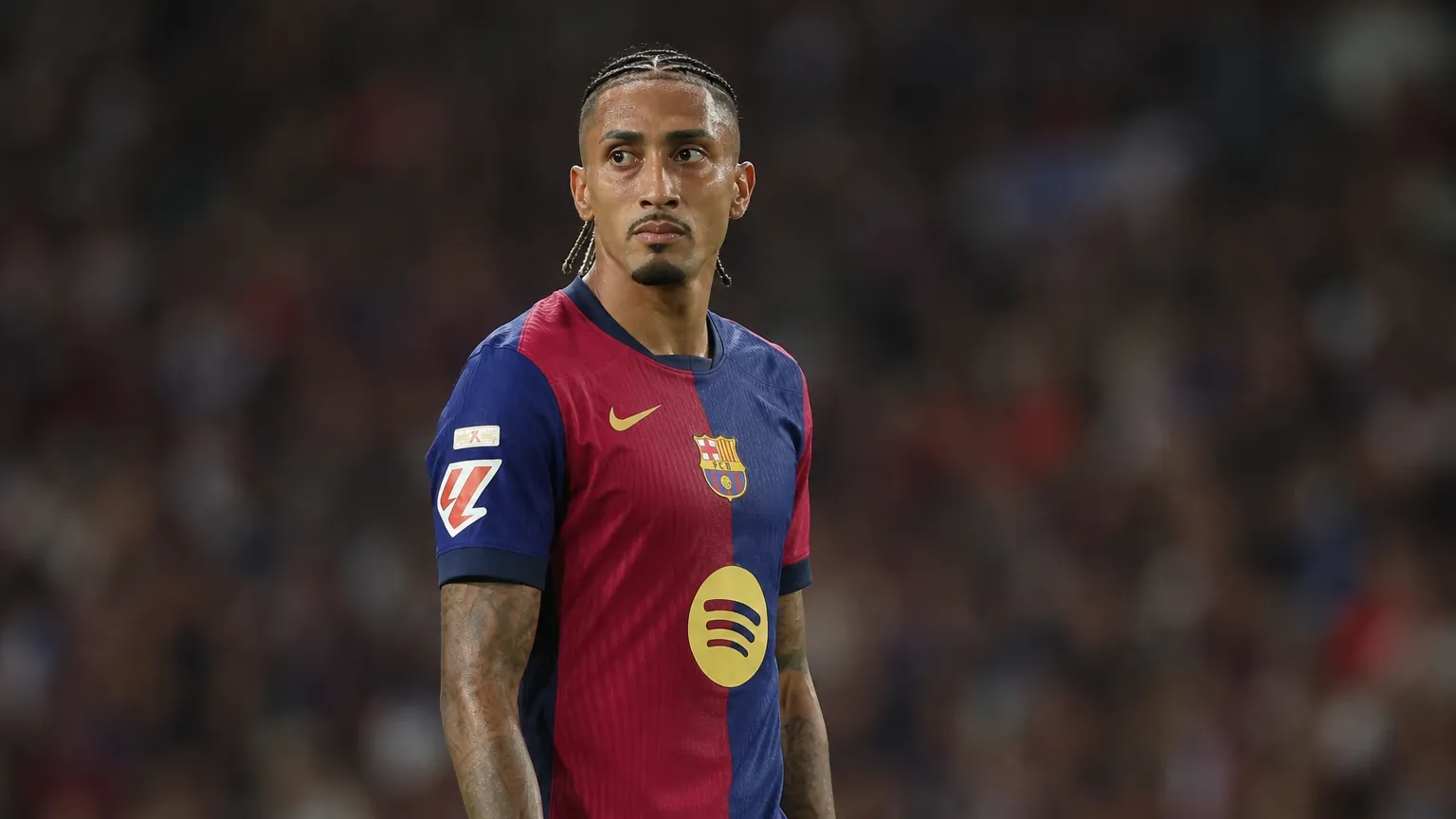 Raphinha in het shirt van Barcelona aan de zijlijn van een stadion.
