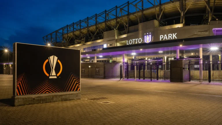 Verlichte ingang van het Lotto Park met een fysiek Europa League-wedstrijdbord.