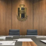 Een metalen KBVB-embleem op een houten wand in een lege vergaderruimte van de voetbalbond.