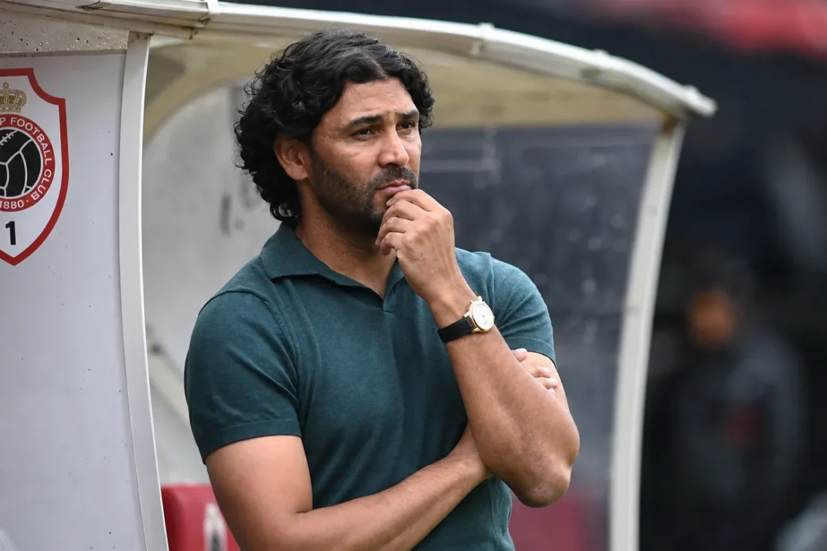 Een coach in donker poloshirt naast de dug-out van Antwerp aan de Bosuil.