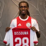 Yves Bissouma toont tijdens zijn Ajax-presentatie een shirt met rugnummer 28.