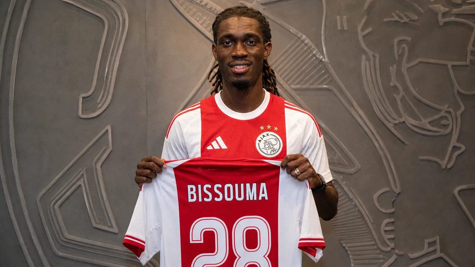 Yves Bissouma toont tijdens zijn Ajax-presentatie een shirt met rugnummer 28.