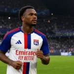 Een speler van Olympique Lyon in een wit wedstrijdtenue op het veld.