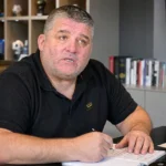 Philippe Albert spreekt als voetbalanalist in een kantoorruimte.