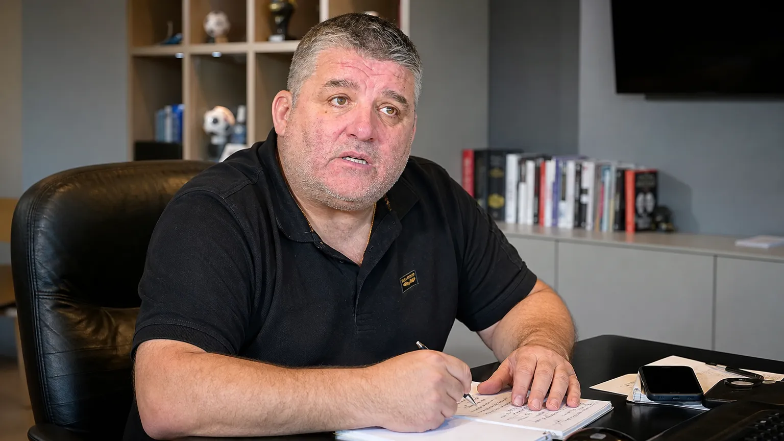 Philippe Albert spreekt als voetbalanalist in een kantoorruimte.