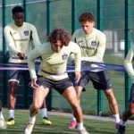Een groep Anderlecht-spelers doet weerstandsoefeningen met elastieken op het trainingscomplex.