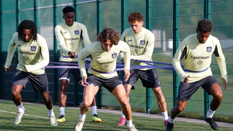 Een groep Anderlecht-spelers doet weerstandsoefeningen met elastieken op het trainingscomplex.