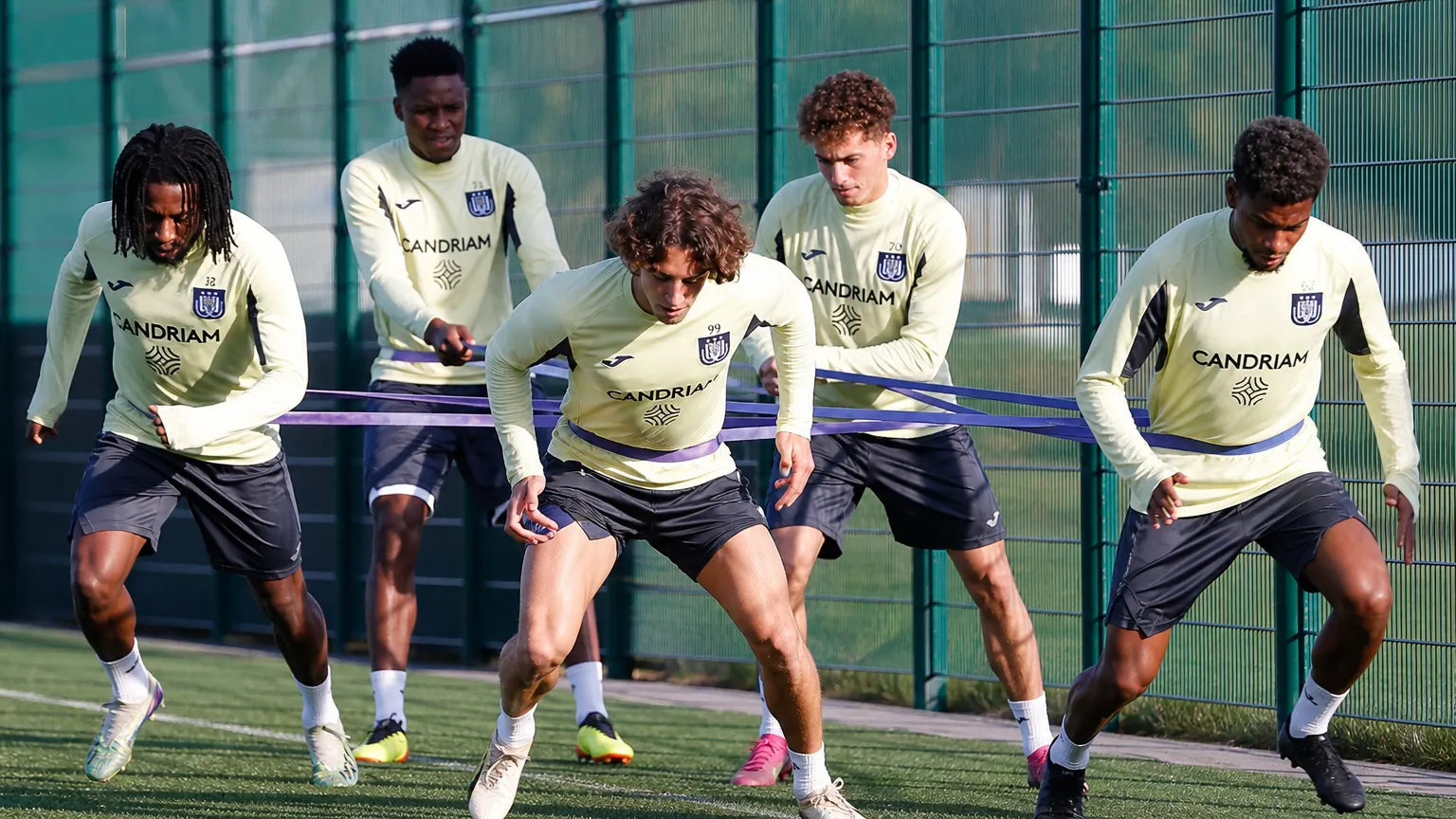 Een groep Anderlecht-spelers doet weerstandsoefeningen met elastieken op het trainingscomplex.