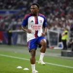 Een speler van Olympique Lyon warmt op het veld op in een vol stadion.