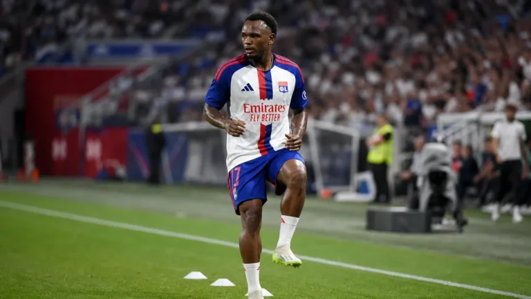 Een speler van Olympique Lyon warmt op het veld op in een vol stadion.