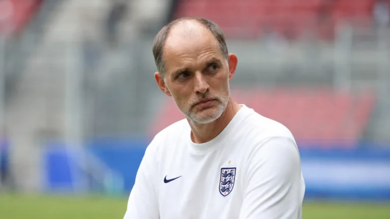 Thomas Tuchel in een wit Engeland-shirt tijdens een rustige terugblik in een stadionomgeving.