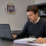 Een medewerker van Anderlecht bekijkt een transferdossier in een operationeel clubkantoor.