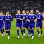 Anderlecht-spelers in paarse tenues tijdens een loopoefening op het veld.