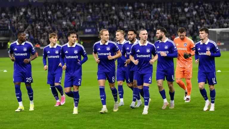 Anderlecht-spelers in paarse tenues tijdens een loopoefening op het veld.