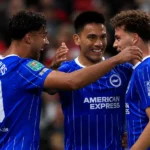 Drie spelers van Brighton vieren samen tijdens een wedstrijd op Old Trafford.