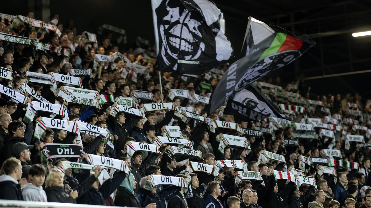 Een groep OHL-supporters zwaait met sjaals en vlaggen in een volle tribune.