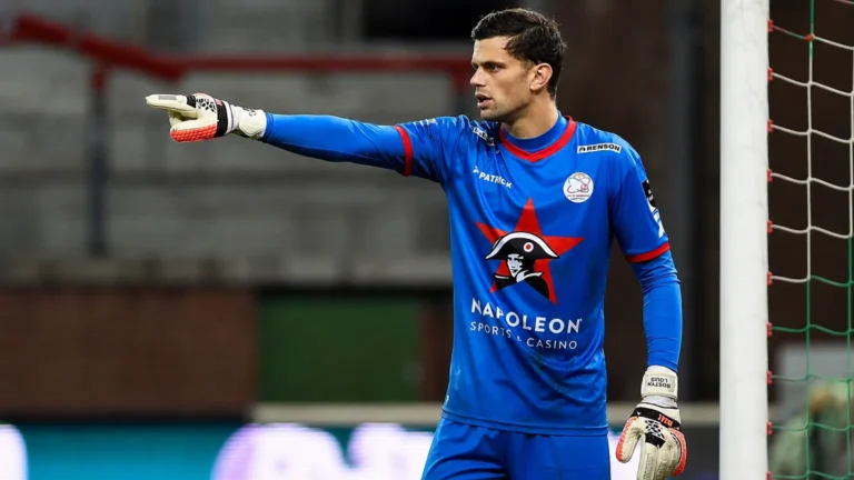 Louis Bostyn in blauw doelmanstenue van Zulte Waregem terwijl hij aanwijzingen geeft op het veld.