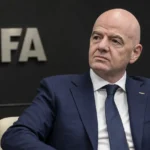 Een niet-spelende FIFA-official in donker pak in een institutionele conferentieomgeving.