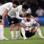 Memphis Depay zit ontgoocheld op het veld terwijl Corinthians-ploegmaats hem opvangen.