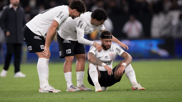 Memphis Depay zit ontgoocheld op het veld terwijl Corinthians-ploegmaats hem opvangen.