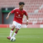 JJ Gabriel in een rood shirt en witte short tijdens een voetbalactie.
