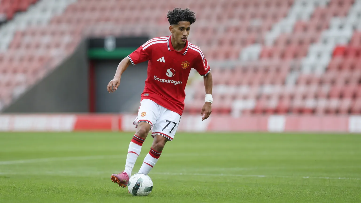 JJ Gabriel in een rood shirt en witte short tijdens een voetbalactie.