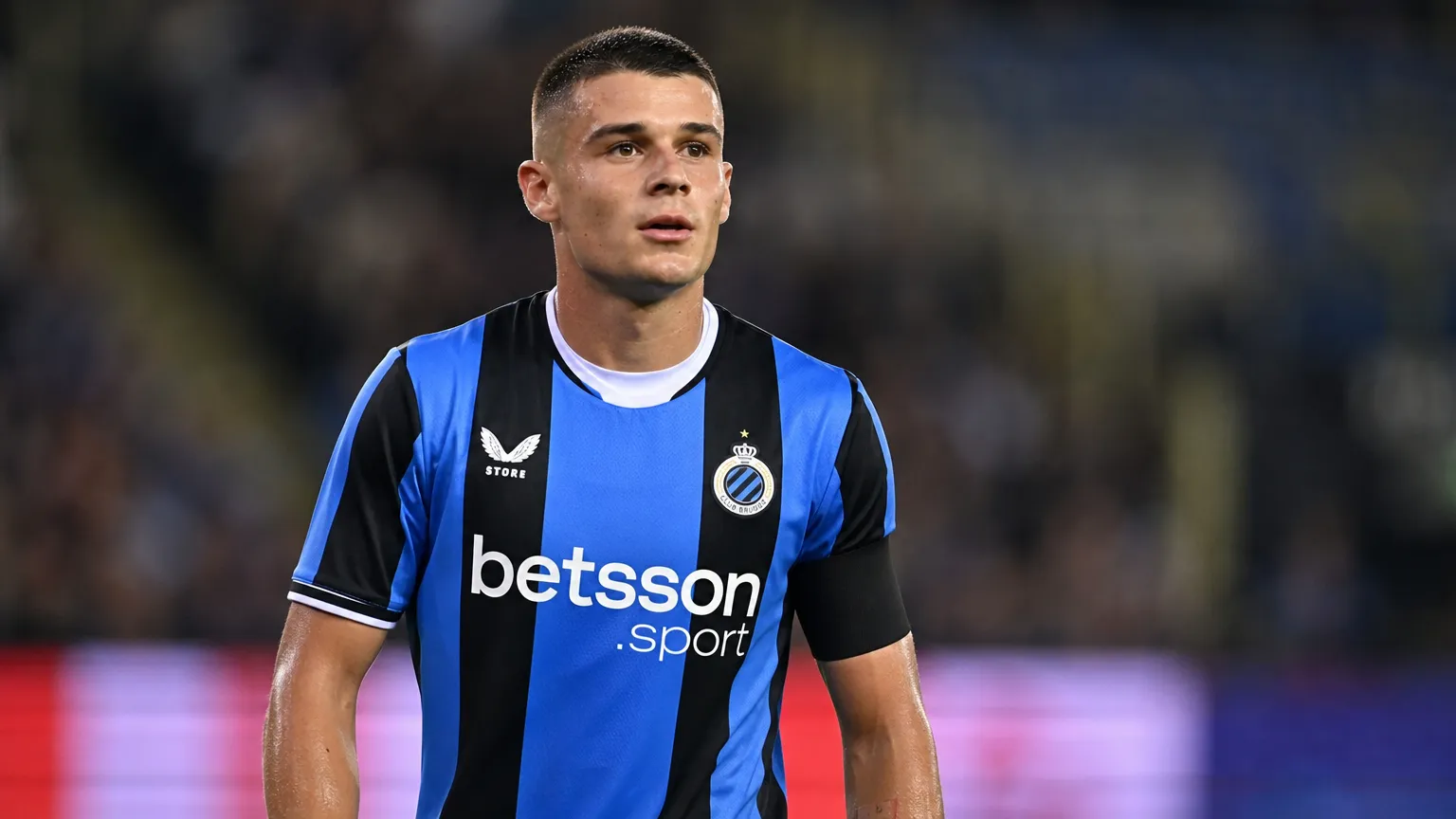 Nicolò Tresoldi in een blauw-zwart voetbalshirt tijdens een rustig moment op het veld.