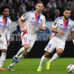 Drie spelers van Olympique Lyon tijdens een wedstrijdmoment met een scheidsrechter.