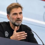 Jürgen Klopp spreekt achter een microfoon tijdens een persconferentie.