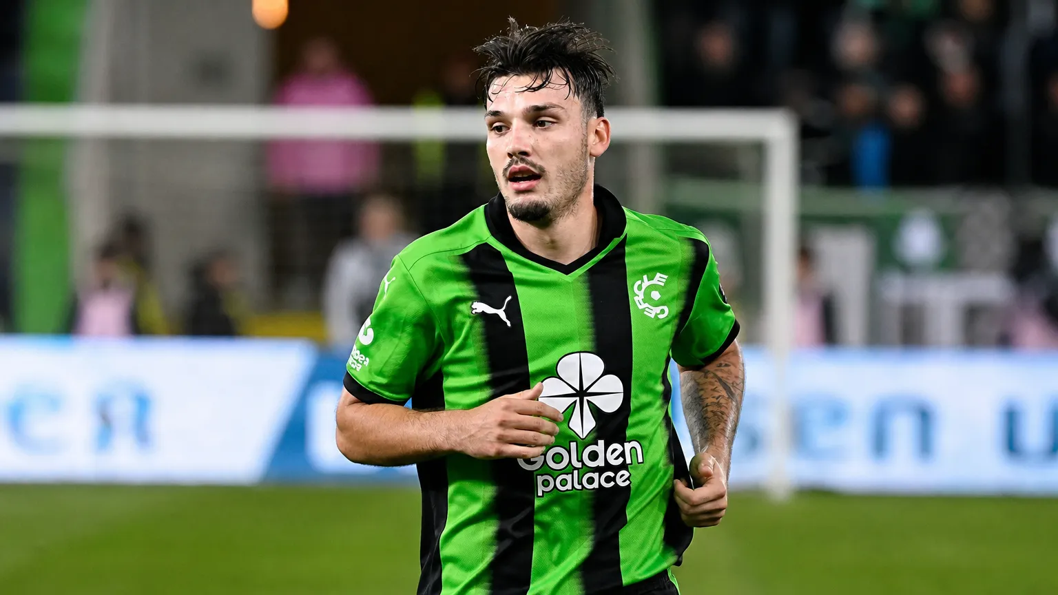 Gary Magnée in een groen-zwart shirt op de rand van een voetbalveld.