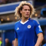 Wout Faes in het blauw van Leicester City aan de zijlijn van een stadion.