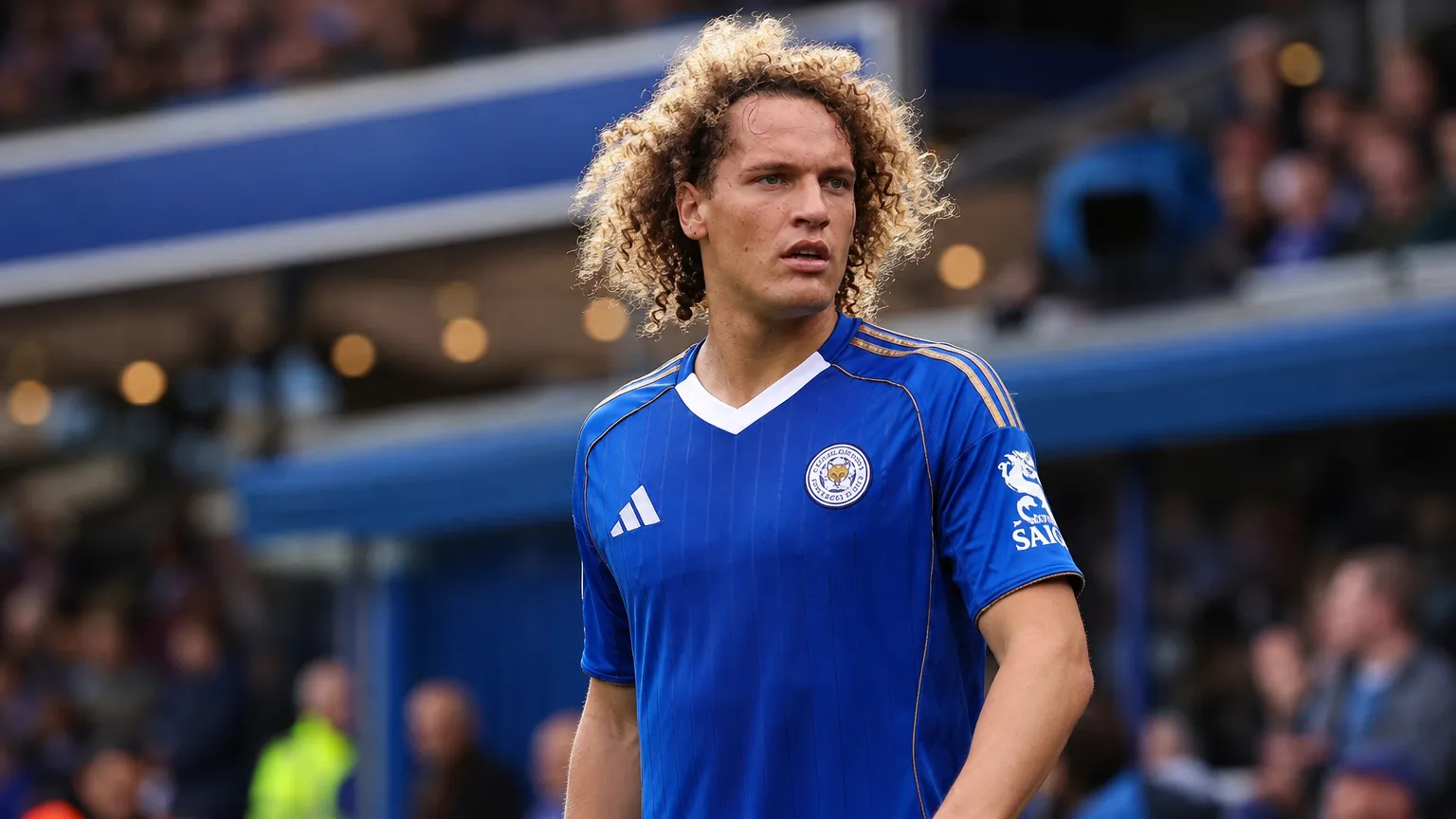 Wout Faes in het blauw van Leicester City aan de zijlijn van een stadion.