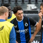 Een groep Club Brugge-spelers in blauw-zwarte wedstrijdkledij naast het veld.