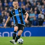 Een Club Brugge-speler in een blauw-zwart gestreept shirt tijdens een wedstrijd.