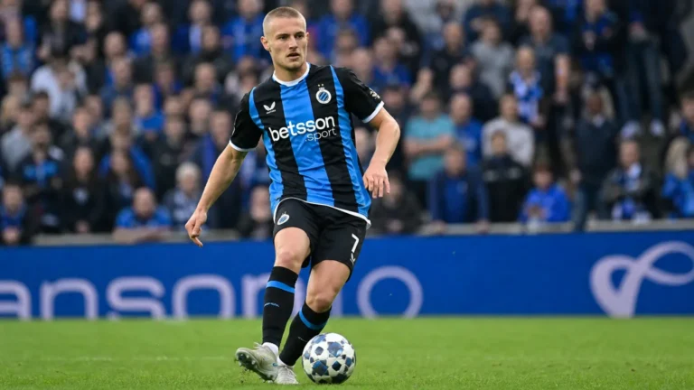 Een Club Brugge-speler in een blauw-zwart gestreept shirt tijdens een wedstrijd.