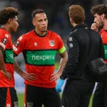 NEC-spelers en een medische stafmedewerker verzamelen zich naast het veld na de wedstrijd.