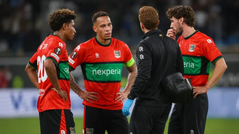NEC-spelers en een medische stafmedewerker verzamelen zich naast het veld na de wedstrijd.