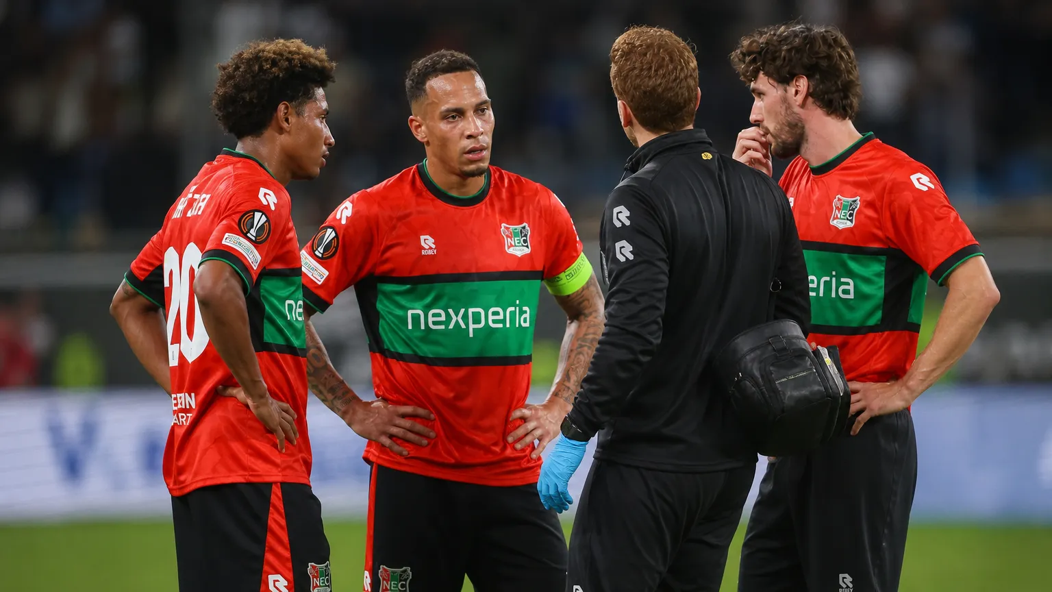 NEC-spelers en een medische stafmedewerker verzamelen zich naast het veld na de wedstrijd.