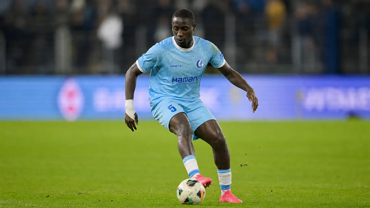 Mouhamed El Bachir Ngom controleert de bal op een verlicht voetbalveld.