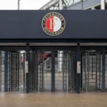Lege toegangspoortjes aan een stadioningang van Feyenoord met een clubembleem op het toegangsbord.