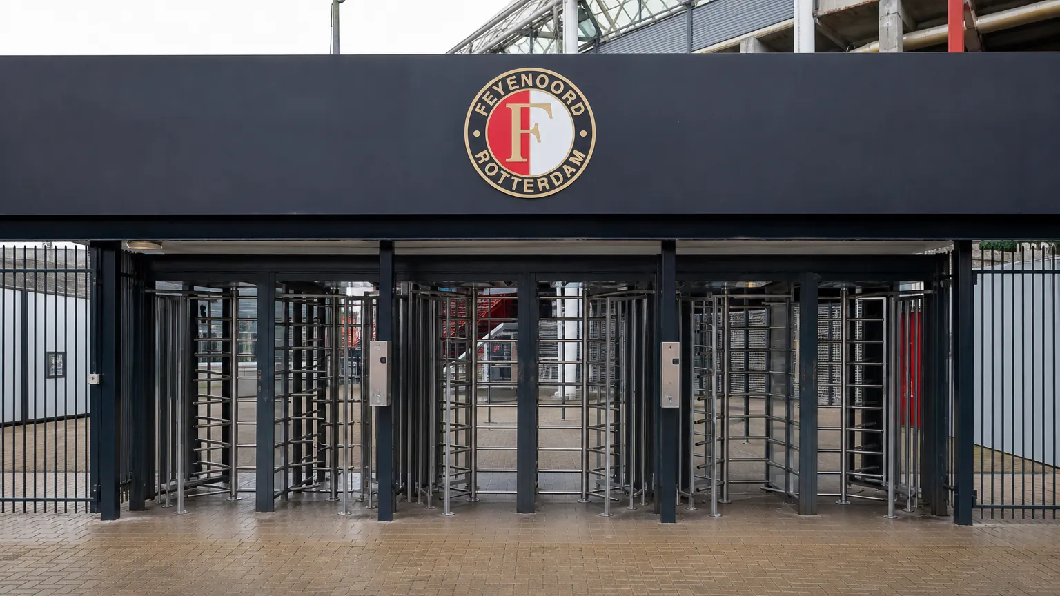 Lege toegangspoortjes aan een stadioningang van Feyenoord met een clubembleem op het toegangsbord.