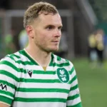 Philippe Rommens in een groen-wit gestreept voetbalshirt aan de rand van het veld.