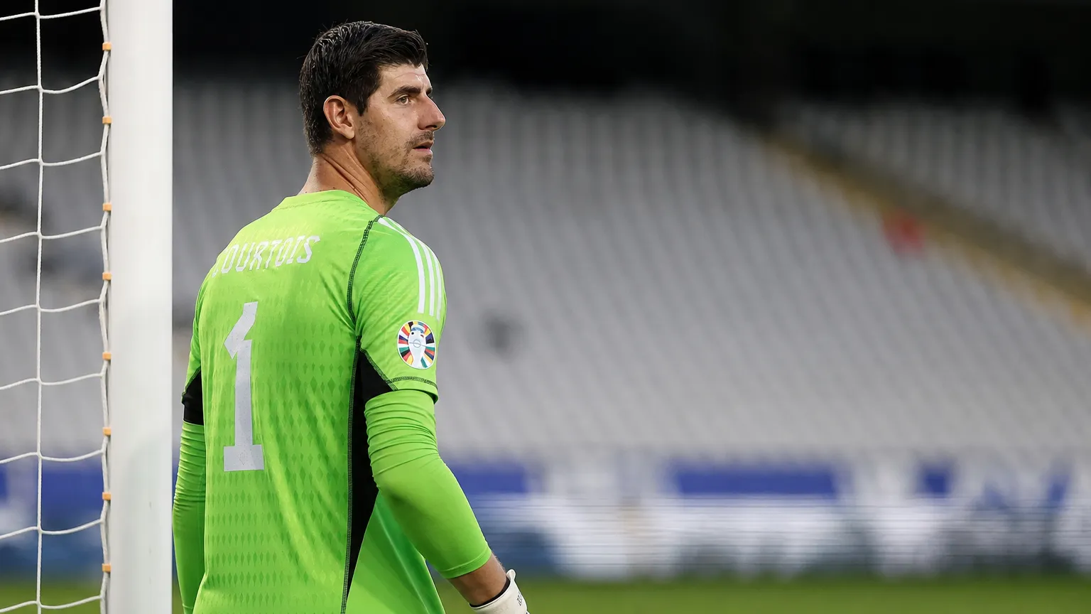 Thibaut Courtois in groen doelmanstenue bij een doel in een stadion.