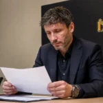 Mark van Bommel bekijkt een selectiedocument in een vergaderruimte van de Belgische nationale ploeg.