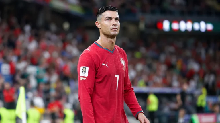 Cristiano Ronaldo in het rode tenue van Portugal aan de zijlijn van een stadion.