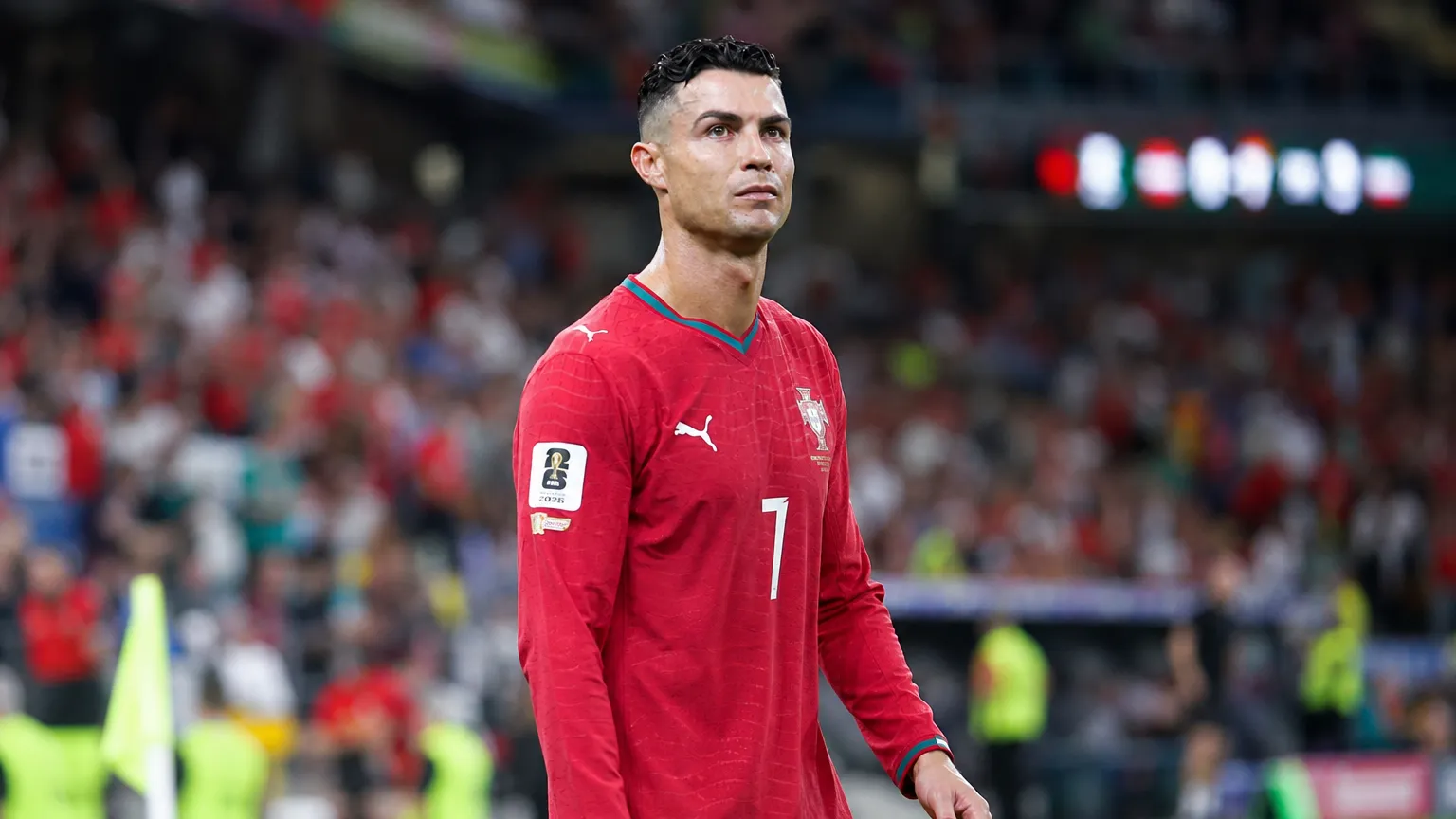 Cristiano Ronaldo in het rode tenue van Portugal aan de zijlijn van een stadion.