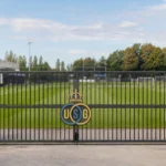 Leeg trainingsveld van Union met het clubembleem aan de toegangspoort.