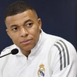 Kylian Mbappé zit tijdens een media-interview achter een microfoon in Real Madrid-kleding.