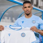 Zinho Gano presenteert het wedstrijdshirt van Al-Akhdood Club.
