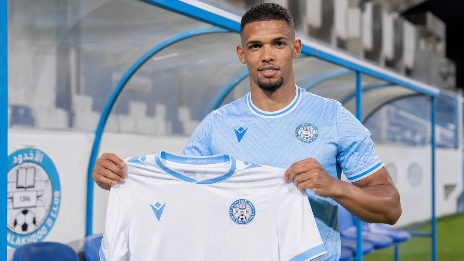 Zinho Gano presenteert het wedstrijdshirt van Al-Akhdood Club.